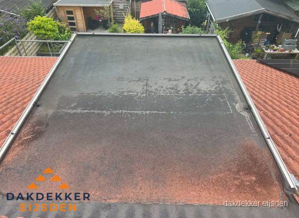 Verouderd plat dak met slijtage tussen schuine daken in Eijsden Verouderd plat dak met slijtage tussen schuine daken in Eijsden