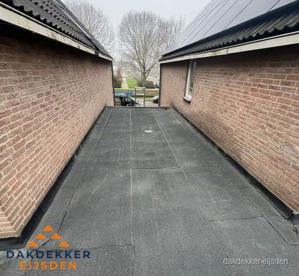 Plat dak met bitumen dakbedekking tussen bakstenen muren in Eijsden