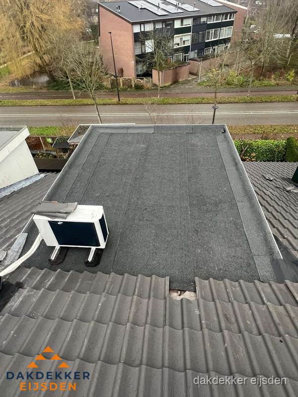 Plat dak inspectie met bitumen bedekking naast schuin pannendak in Eijsden