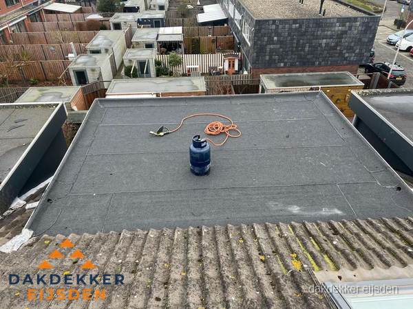 Plat dak met nieuwe bitumen dakbedekking en brandgereedschap in Eijsden